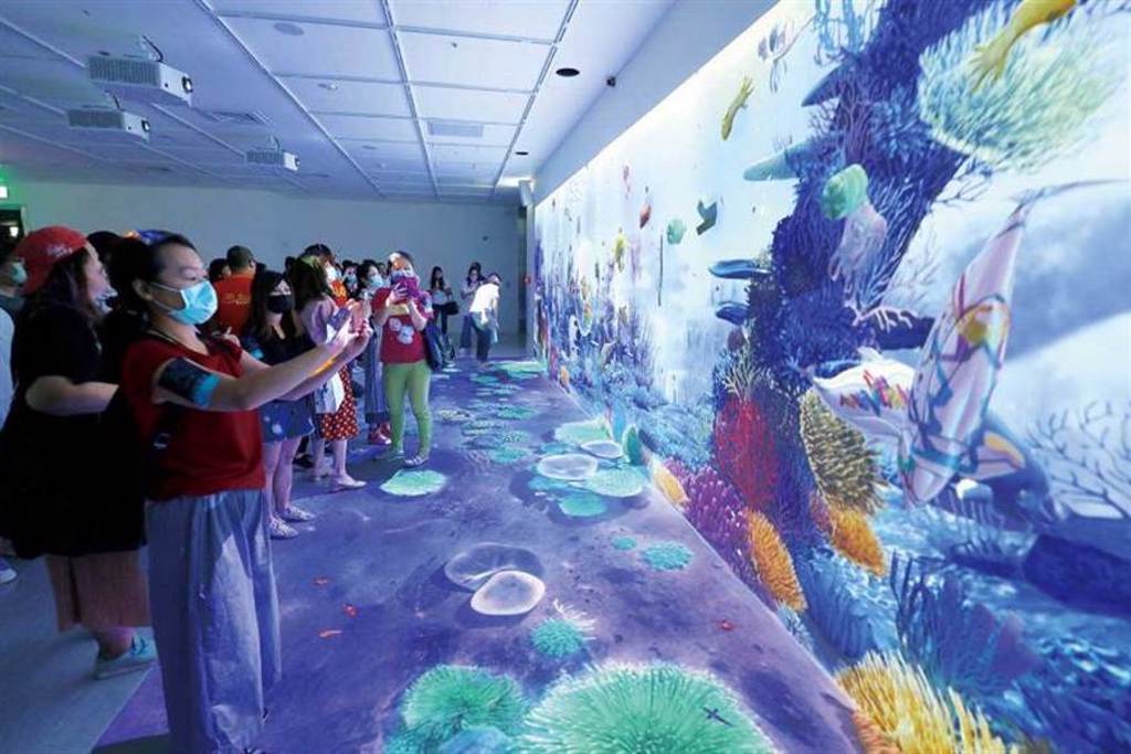 來到「虛實互動」區，遊客可在現場的平板電腦上，透過益智遊戲與彩繪軟體，組合出海洋生物，並投射到牆上的虛擬海洋中。（圖／于魯光攝）