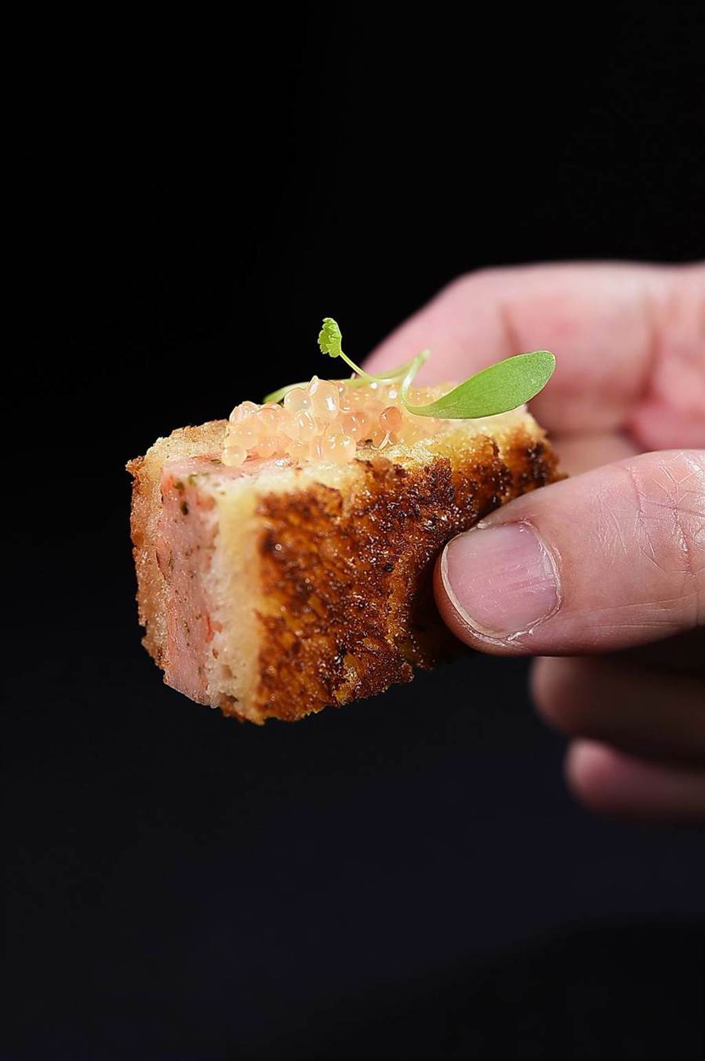 〈蝦多士〉是將蝦肉慕斯夾進片薄的布里歐麵包中，再以澄清奶油兩面煎出金黃香酥，再再昆布鹽提味， 搭配手指檸檬、香菜苗呈現。（圖／姚舜）
