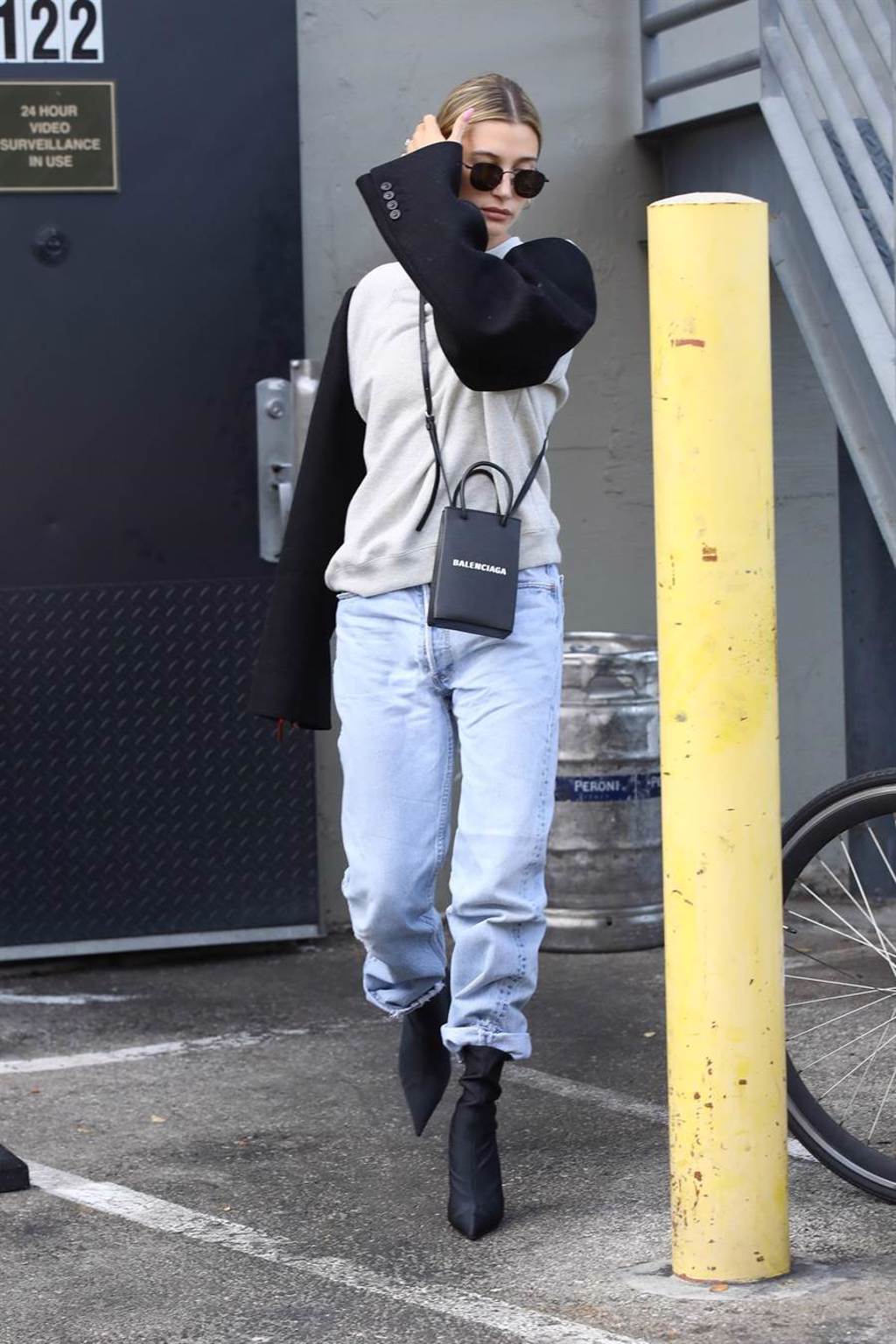 海莉·鲍德溫穿插肩衛衣搭配牛仔裤配Balenciaga挎包，時尚又率性（視覺中國提供）