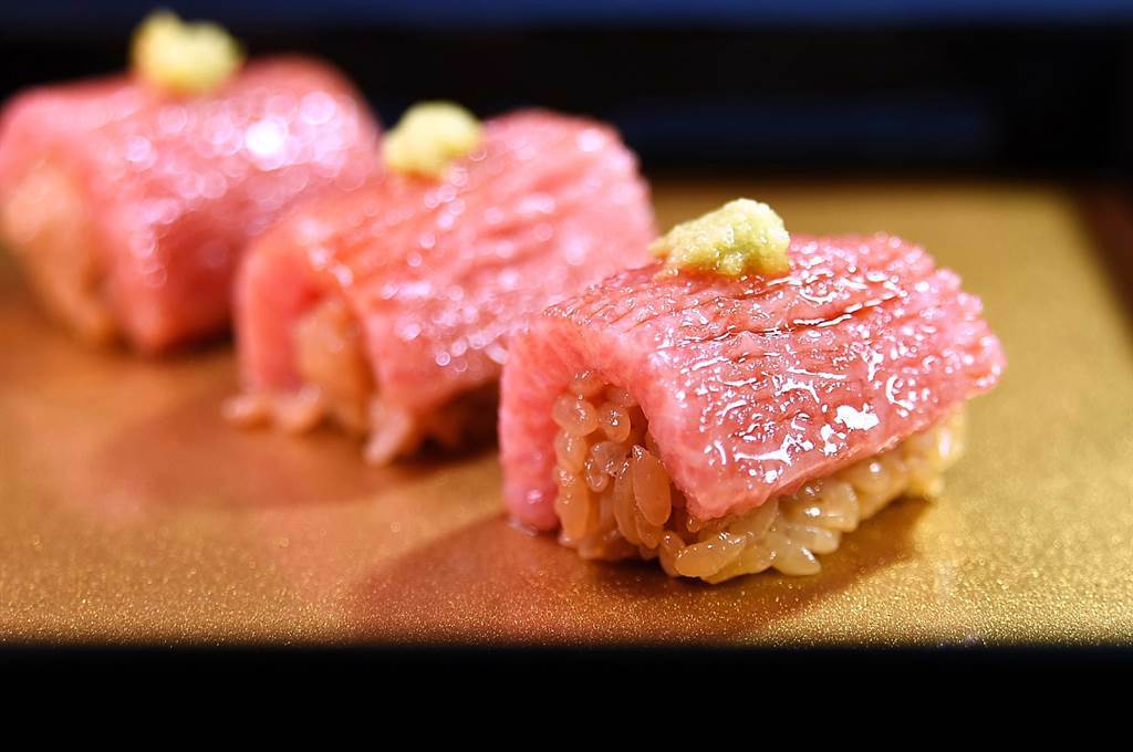 〈米匠〉的〈黑鮪魚大腹握壽司〉是油脂豐富的O-toro，廚師在魚肉上以刀功畫出細紋再淋上特製醬汁並點綴山葵泥，搭配紅醋飯呈現。（圖／姚舜（