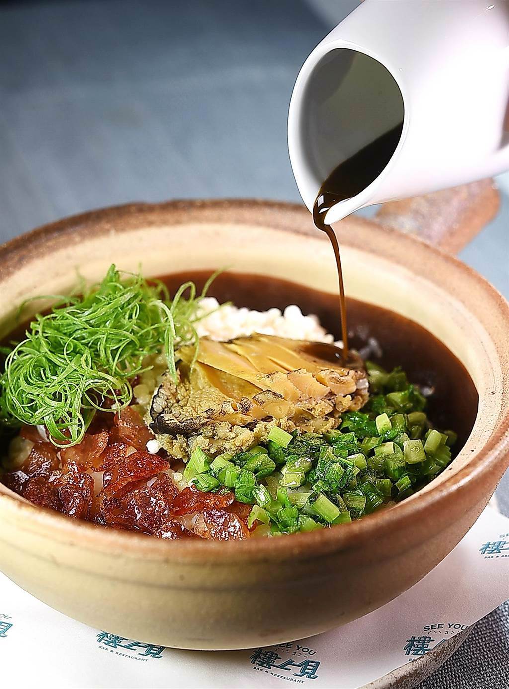 〈樓上見〉的〈鮑魚飯〉，結合了港式「煲仔飯」與上海「菜飯」的精神呈現，醬油則是用日式甜醬油與魚肝熬製。（圖／姚舜）