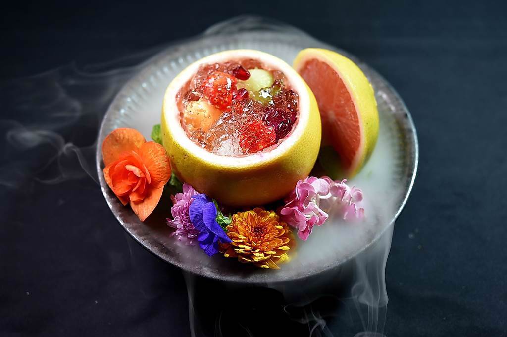〈渡邉〉這一季的餐後甜點是用薄荷葉浸煮取汁作成晶凍，搭配當令的草莓、雙色哈密瓜和火龍果呈現，並以食用花卉和乾冰傳遞吸睛效果。（圖／姚舜）