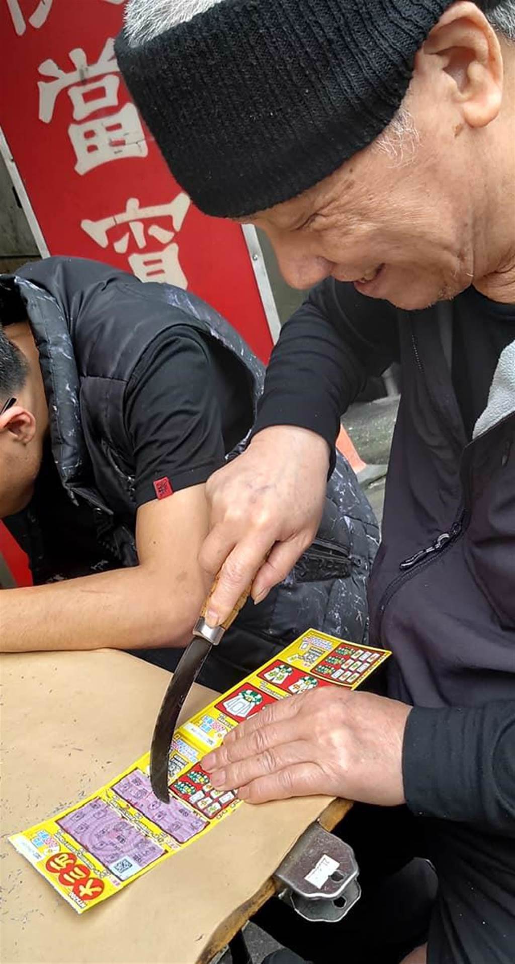 一位民眾在台北汐止街頭看到一位老伯伯用刀子在玩刮刮樂。(摘自爆廢1公社)