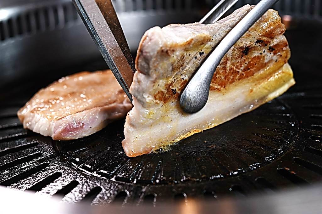 〈虎三同〉服務人員代客燒烤豬五花時，會將豬皮貼著鍋面逼油，使之更酥脆。（圖／姚舜）