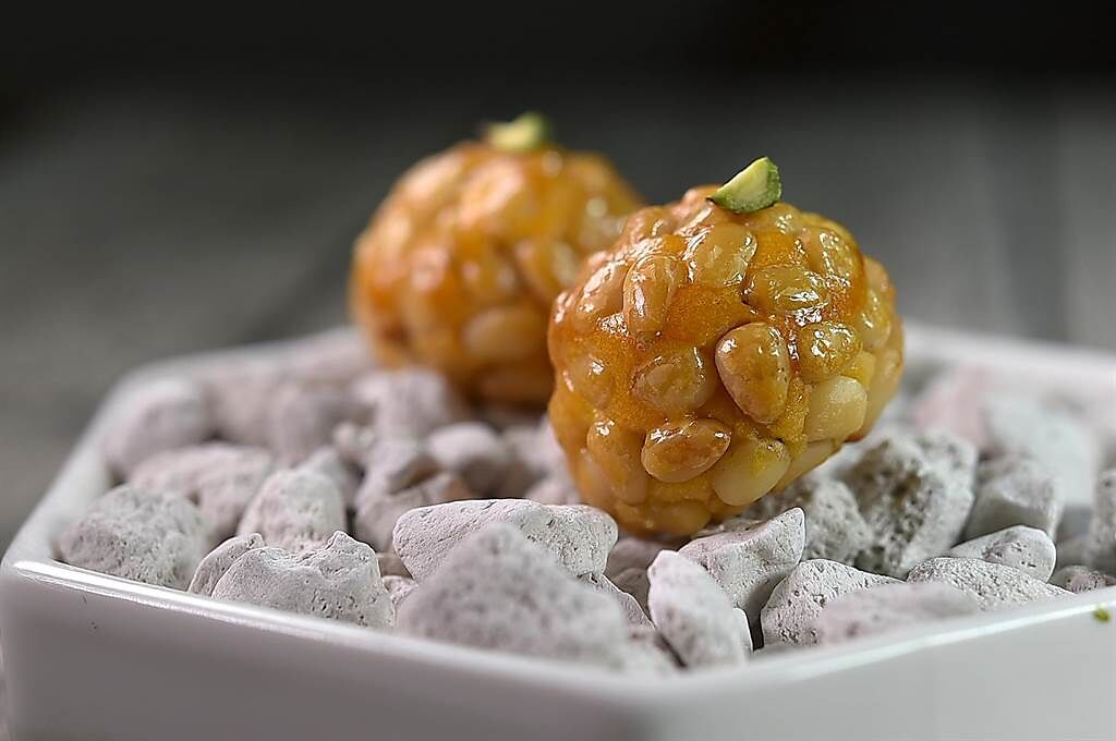 〈alam〉的新甜點〈松子杏仁球〉，球體是杏仁粉拌地瓜泥作的杏仁糕，然後涮了蛋黃、沾附松子後爐烤，是西班牙安道爾很傳統的甜點。（圖／姚舜）