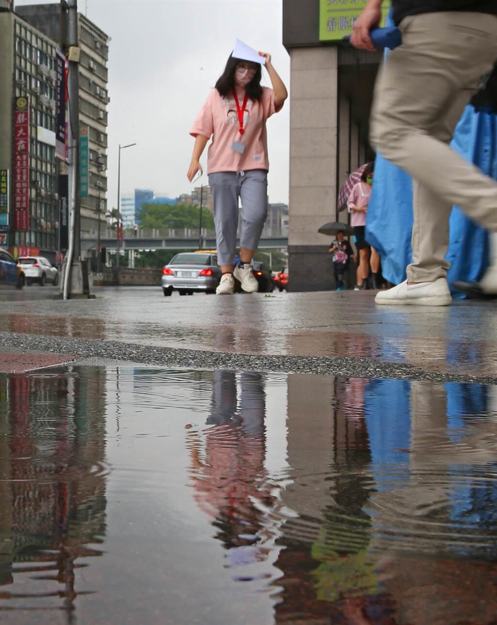 隨著鋒面接近，28日早上開始台北市就出現短暫陣雨，路上行人用手遮雨跑向騎樓，市區雖有降雨積水但對水庫旱象仍無太大幫助。（陳君瑋攝）