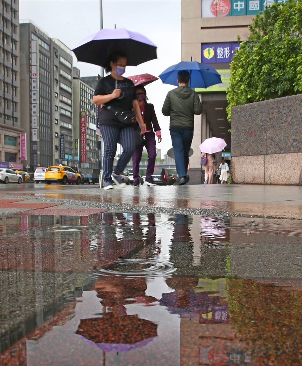隨著鋒面接近，28日早上開始台北市就出現短暫陣雨，路上行人紛紛撐起傘來遮雨，市區雖有降雨積水但對水庫旱象仍無太大幫助。（陳君瑋攝）