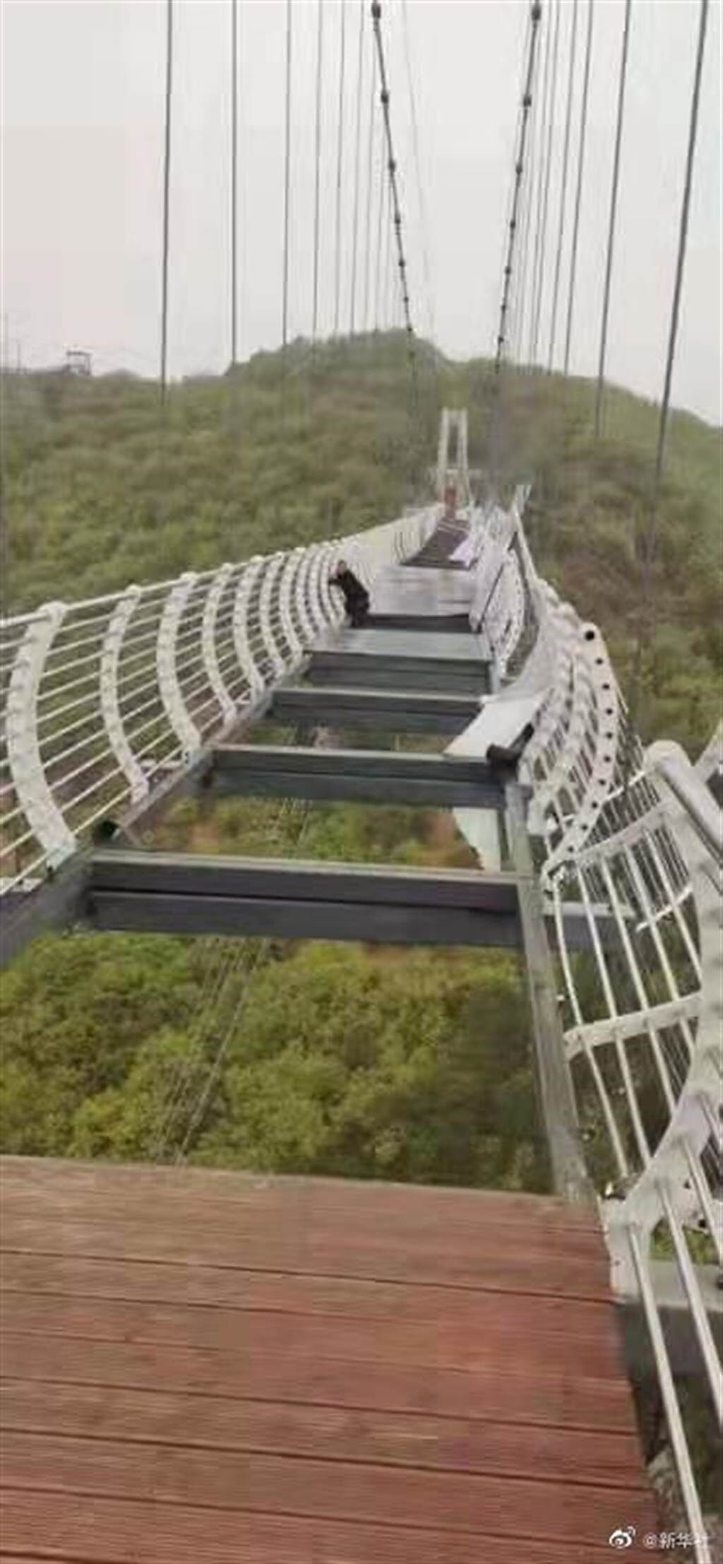 大陸吉林省一處風景區所設置的高空玻璃吊橋，近日因大風將玻璃棧道吹起，讓上面正在行走的遊客嚇到腿軟。（圖／微博@新华社）