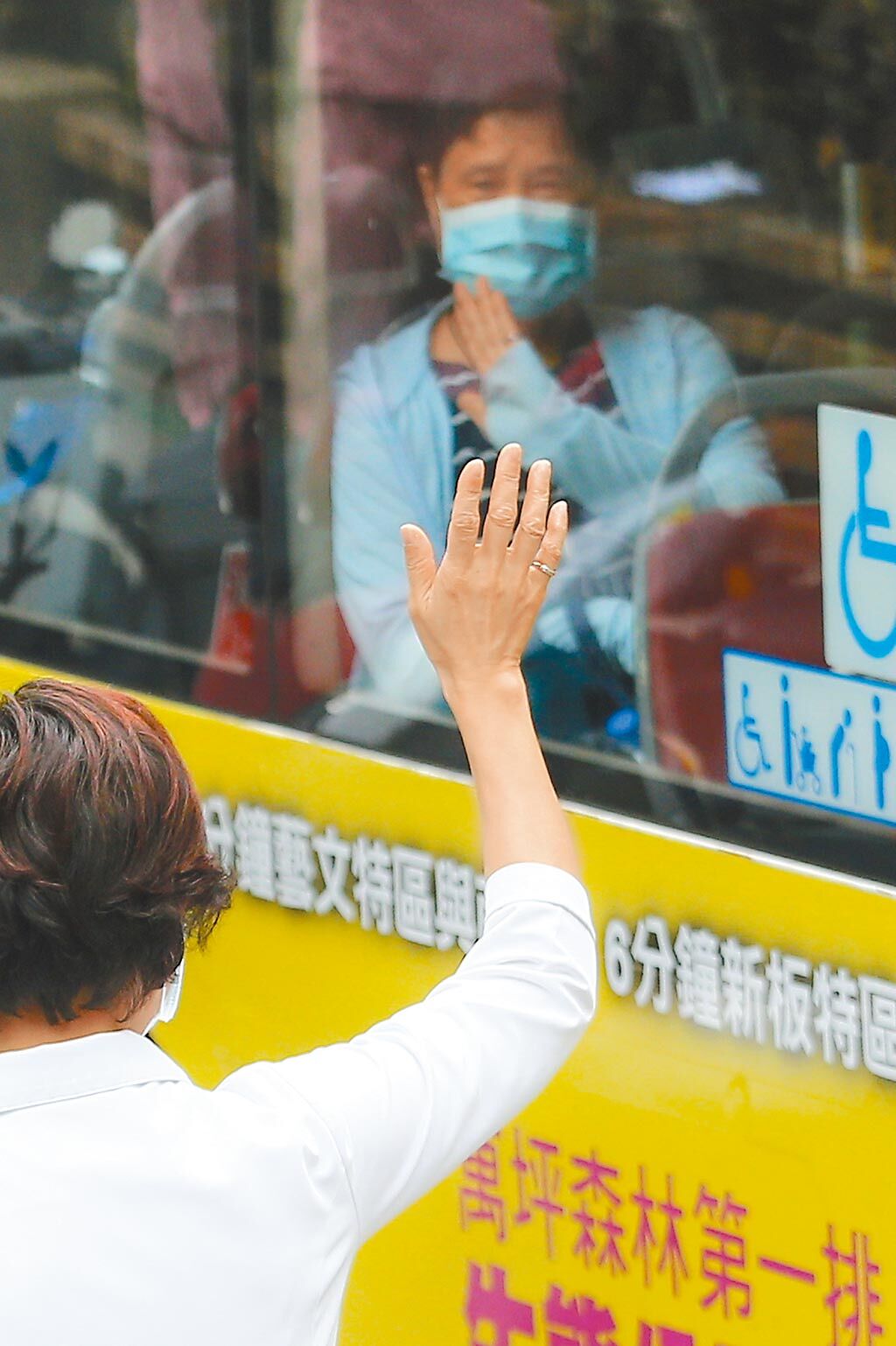 台北市和平醫院通報2名住院病患確診為新冠肺炎，致使22位相關醫護人員需接受隔離，前往防疫旅館的醫護人員14日搭乘防疫專車，護理長劉翠瑤在發車時向同仁揮手喊話「加油」。（杜宜諳攝）