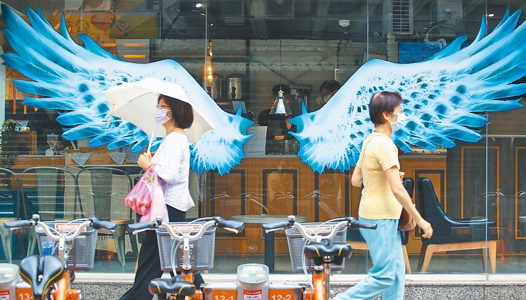 新冠肺炎疫情持續延燒，24日台北街頭行人不多，圖為兩位台北市民戴著口罩走過商店櫥窗。（陳俊吉攝）