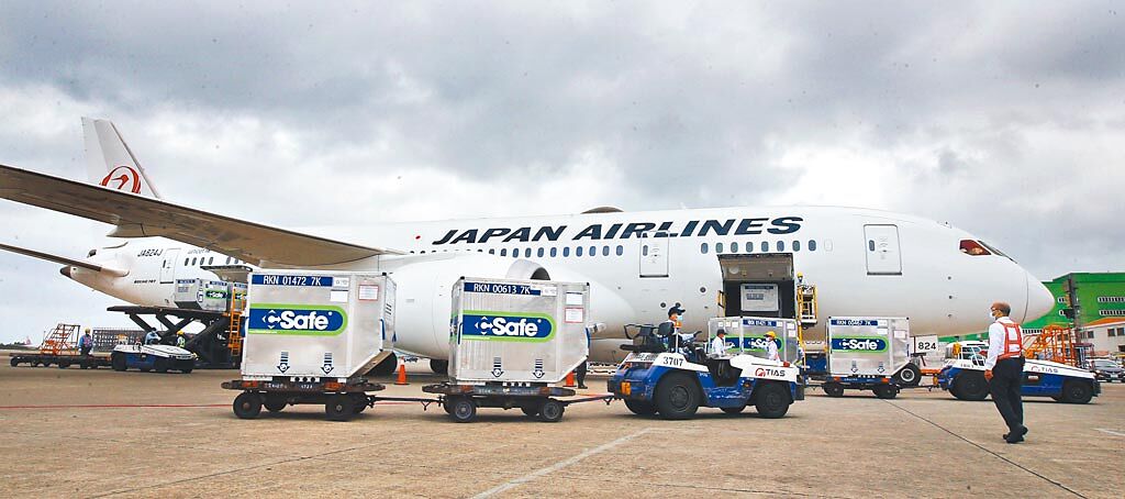 日本捐贈台灣首批124萬劑AZ疫苗，4日由日航班機運抵桃園機場，圖為地勤人員一一卸下疫苗的冷凍貨櫃。（范揚光攝）