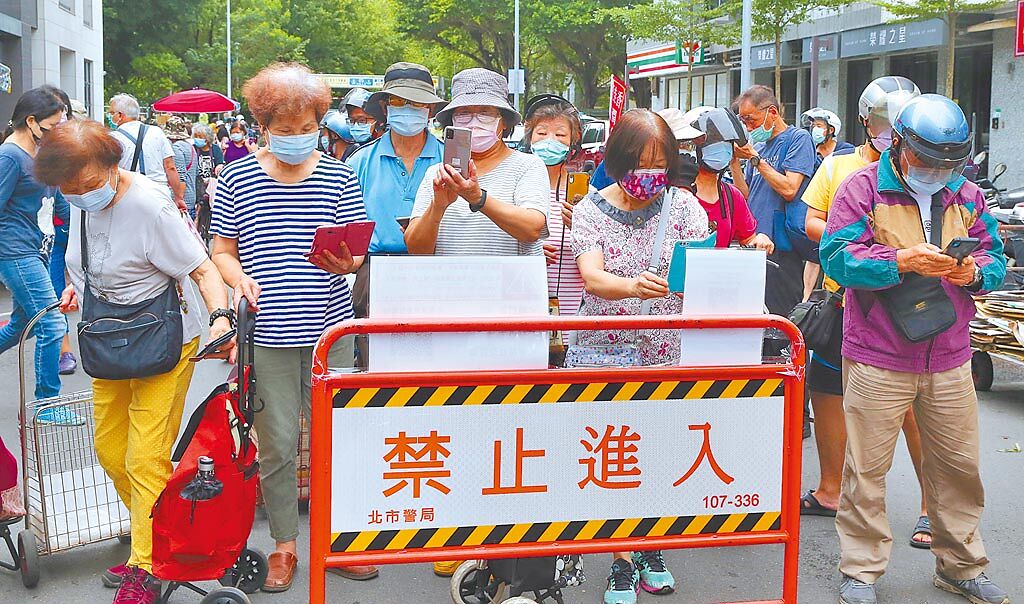 新冠肺炎疫情延燒，台北市針對傳統市場進行人流管制，濱江市場6日員警要求民眾用手機登錄後才能進入採買。（陳君瑋攝）