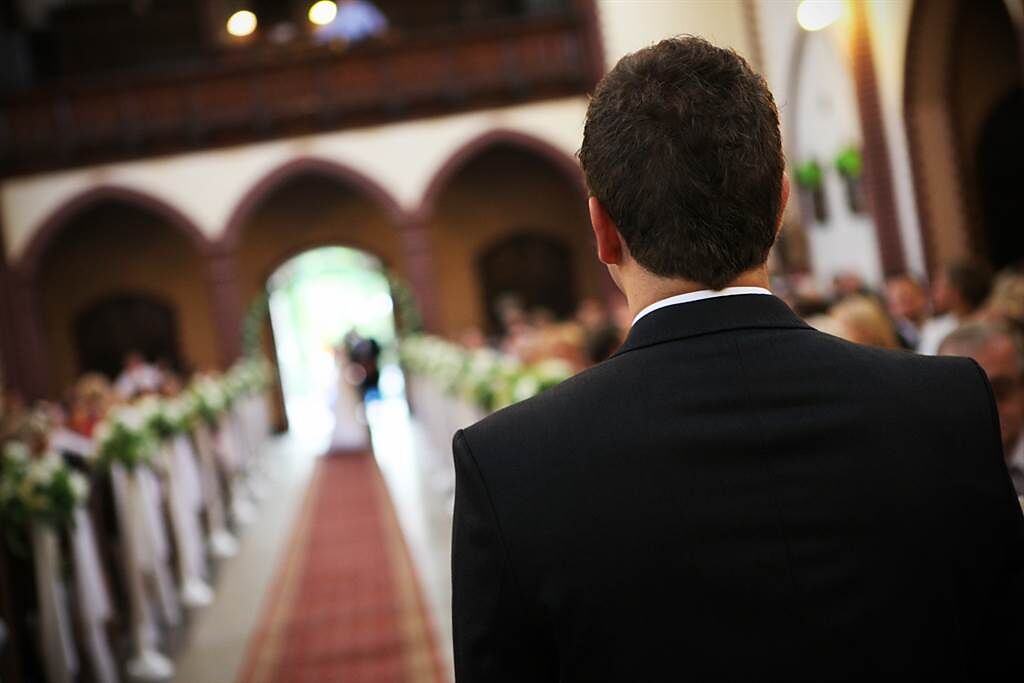 美國一名新郎在新娘走紅毯的時候，從口袋掏出手機低頭查看。(示意圖/達志影像)