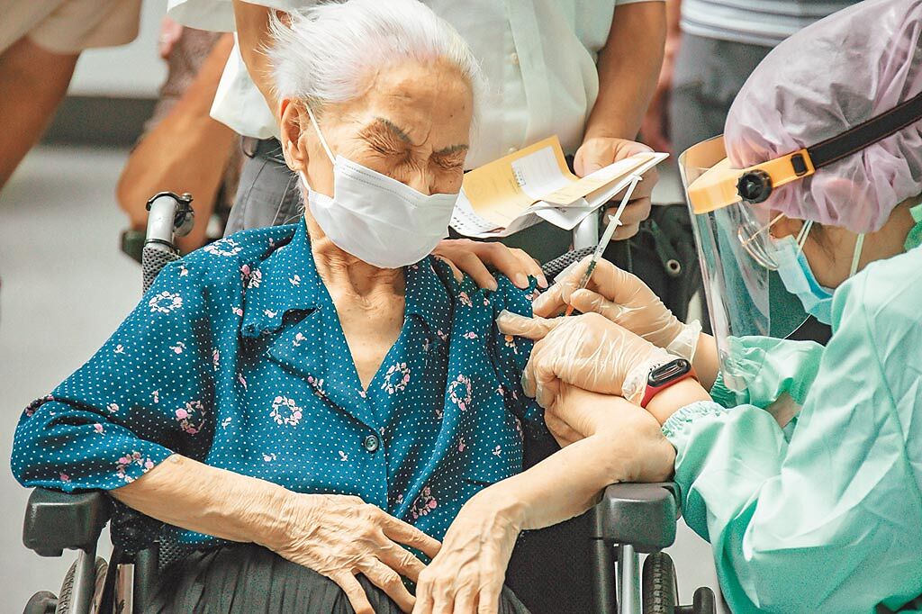 日本捐贈台灣124萬劑AZ疫苗，15日台北市開放85歲以上長者、65歲以上具原住民身分長者施打這批疫苗，新光醫院在國立科學教育館替民眾施打，圖為年長民眾坐著輪椅接種時露出疼痛表情。（羅永銘攝）