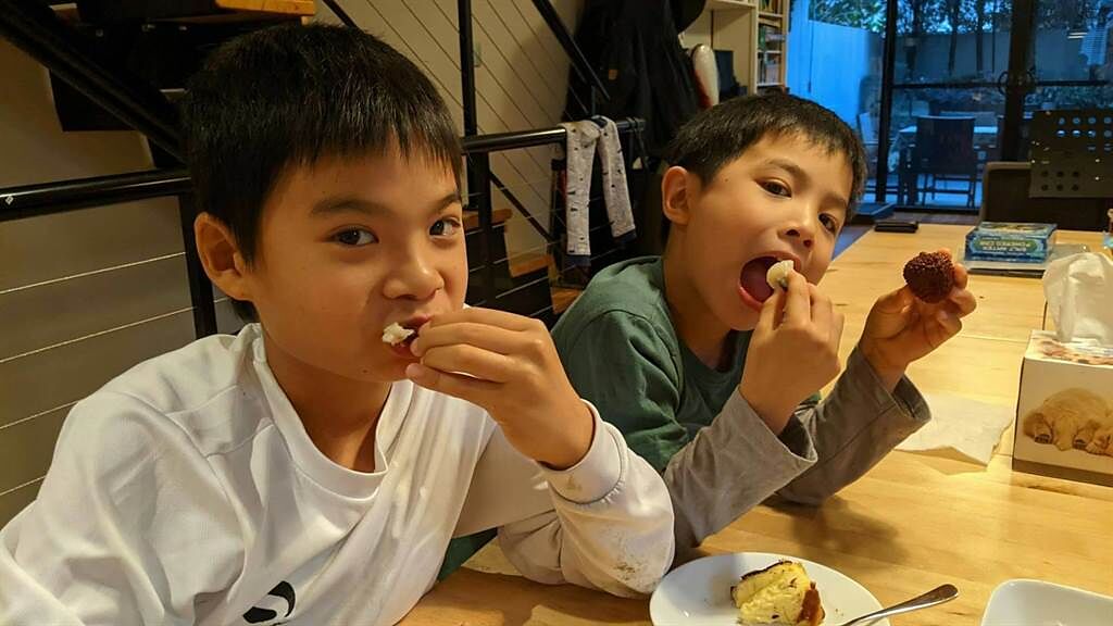 旅澳台僑企業家的小孩開心的吃著家鄉空運來到玉荷包。（高雄市農業局提供／林雅惠傳真）