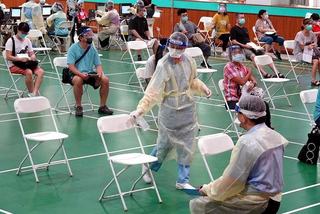 工作人員在接種者離席後立刻上前清消座椅。（黃世麒攝）
