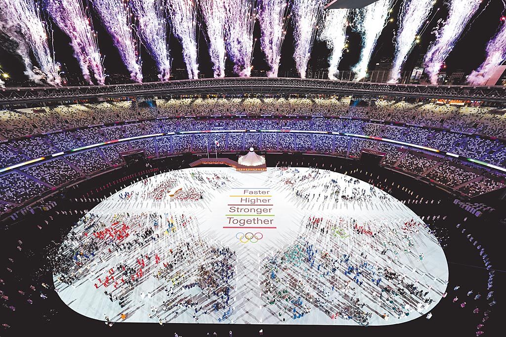 2020東京奧運開幕式，各國運動員在電玩交響樂中進入新國立競技場後，場中央打出更快、更高、更強的奧運格言，及面對新冠疫情要「更團結」的口號。（美聯社）