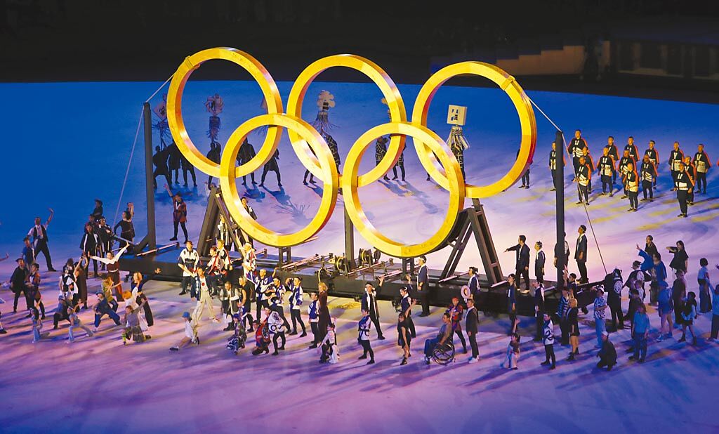 東京奧運開幕式「永恆傳承」表演，由木匠拉出木造五環，木頭來源是1964年首次東京奧運各國代表團種下的樹，展現從1964年傳承到2021年的意象。（季志翔攝）