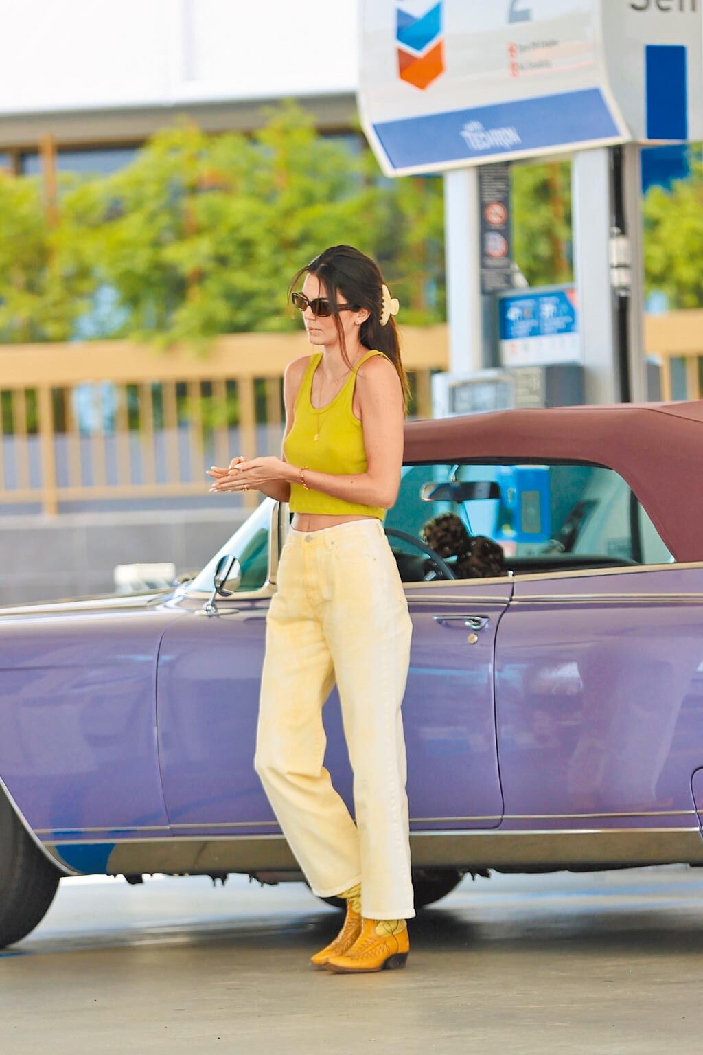坎達兒珍娜身穿酪梨色短版背心搭配白色牛仔褲、Dsquared2復古黃色牛仔靴，開著她的凱迪拉克上街。（CFP）