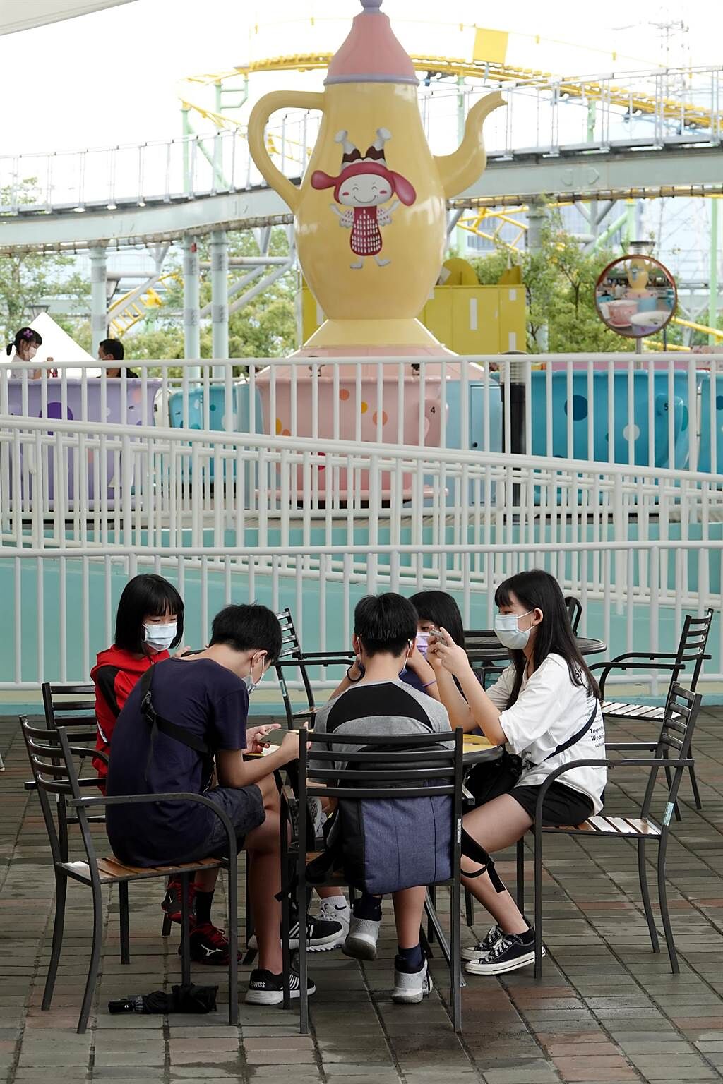因執行嚴格的防疫措施，讓等待的時間拉長，一群青少年趁著空檔，圍在一起玩手機遊戲打發時間。（黃世麒攝）