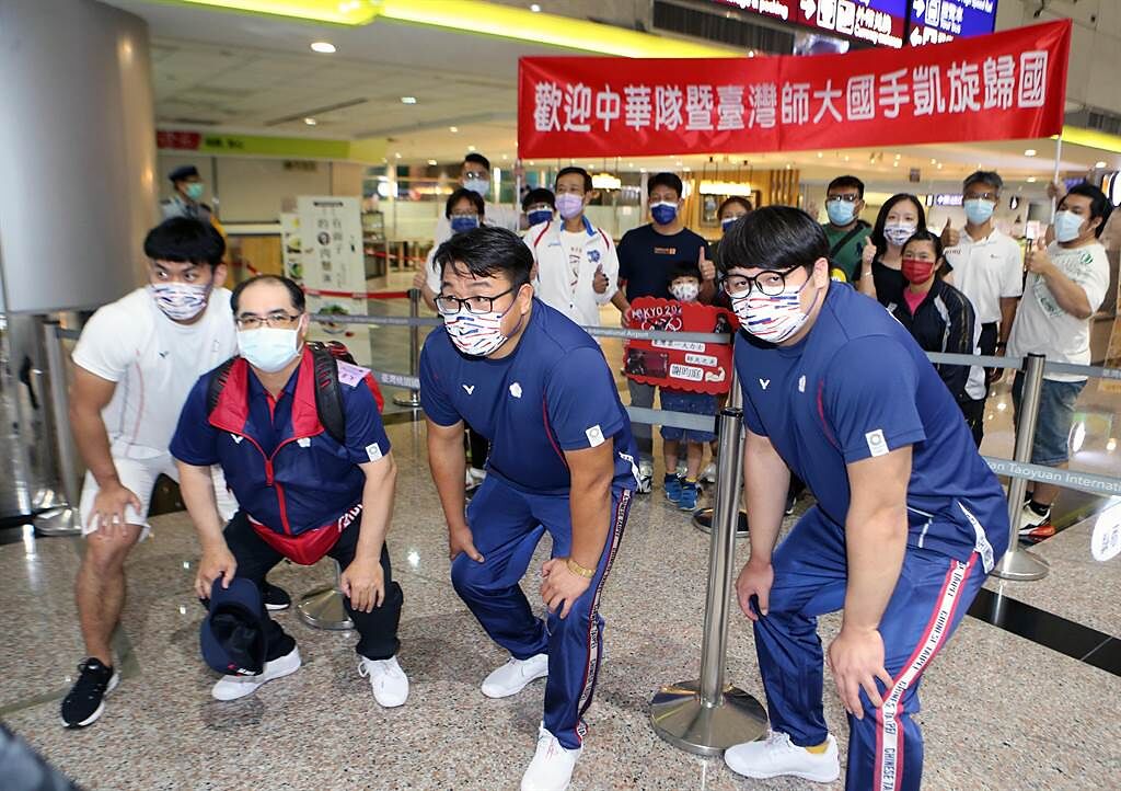 金牌教練林敬能（左二）、黃達德（右二）與選手陳柏任（左一）、謝昀庭（右一）在入境大廳與接機親友合照。（陳麒全攝）