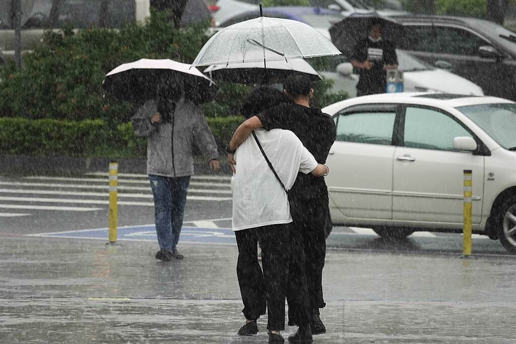 全台降下豪大雨，民眾路過高速公路服務區，彼此相擁撐傘上洗手間。（黃子明攝）