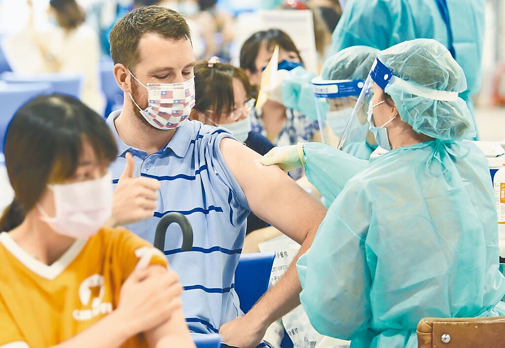 社會上質疑新冠「死亡黑數」的聲音從未減少。圖為台北市花博爭豔館接種站9日為補教業者專案施打疫苗，外籍民眾在完成接種後，豎起大拇指對醫護人員表達謝意。（陳俊吉攝）