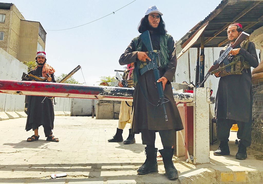 幾名手持武器的塔利班戰士17日在美國駐阿富汗大使館附近一處崗哨戒備。該崗哨原是由美軍駐守。（美聯社）