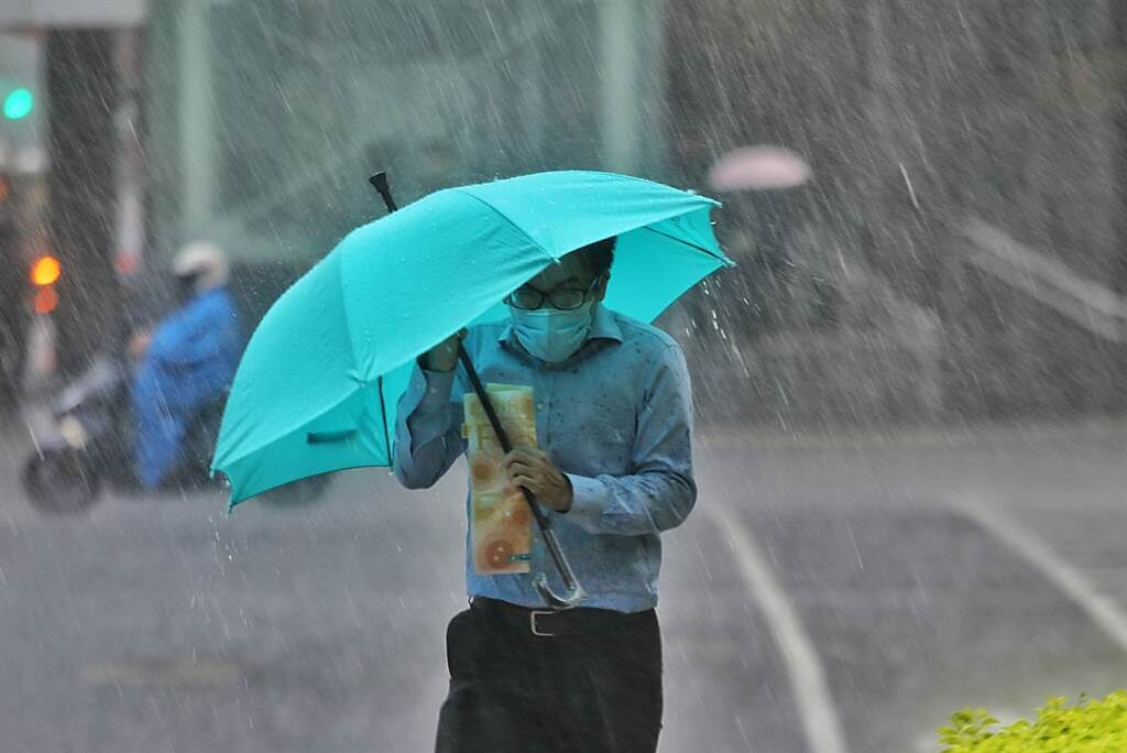 中央氣象局發布豪雨特報，台北市午後突如其來的傾盆大雨讓許多來不及防範的騎士只能加速離去，還有許多民眾只能縮著身體躲在雨傘下。（杜宜諳攝）