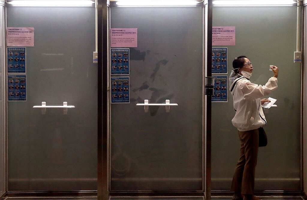 在桃園機場第二航廈外的旅遊泡泡專用採檢站中，剛下機的旅客正在採集唾液檢體。（范揚光攝）