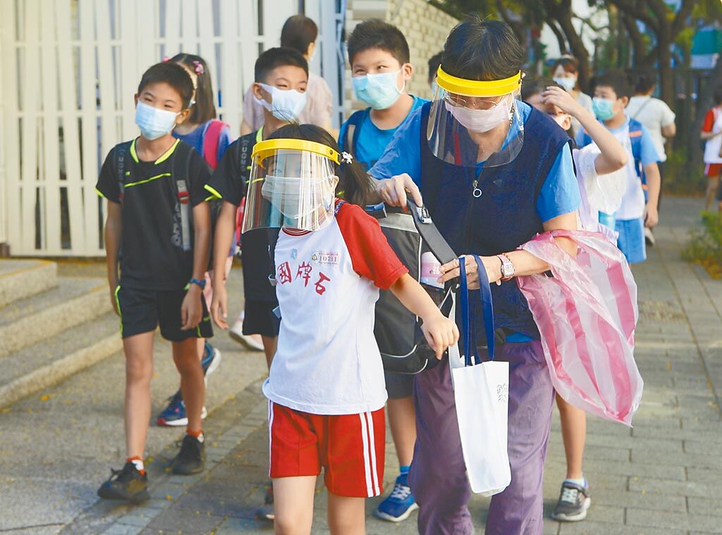 歷經近百日停課加上暑假，台北市石牌國小昨為返校日，有些學生除了口罩外，並佩戴面罩進入校園。（張鎧乙攝）