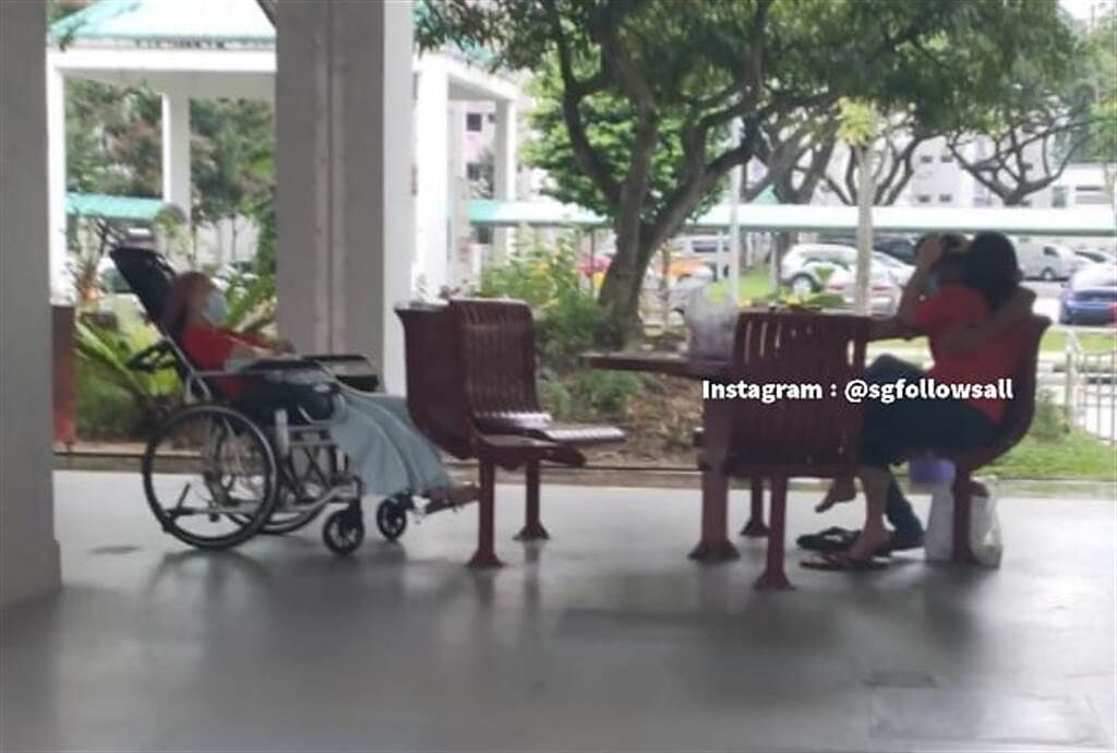 新加坡一名女看護將坐輪椅的老婦人丟在一旁，坐在一名男子的大腿上激吻。(圖/翻攝自Instagram/@sgfollowsall)