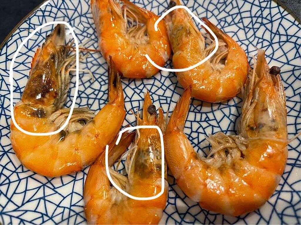 民眾驚見盤內的蝦頭顏色變黑，擔心不新鮮，因此猶豫是否要吃下肚。（圖／翻攝自臉書《爆系知識家》）