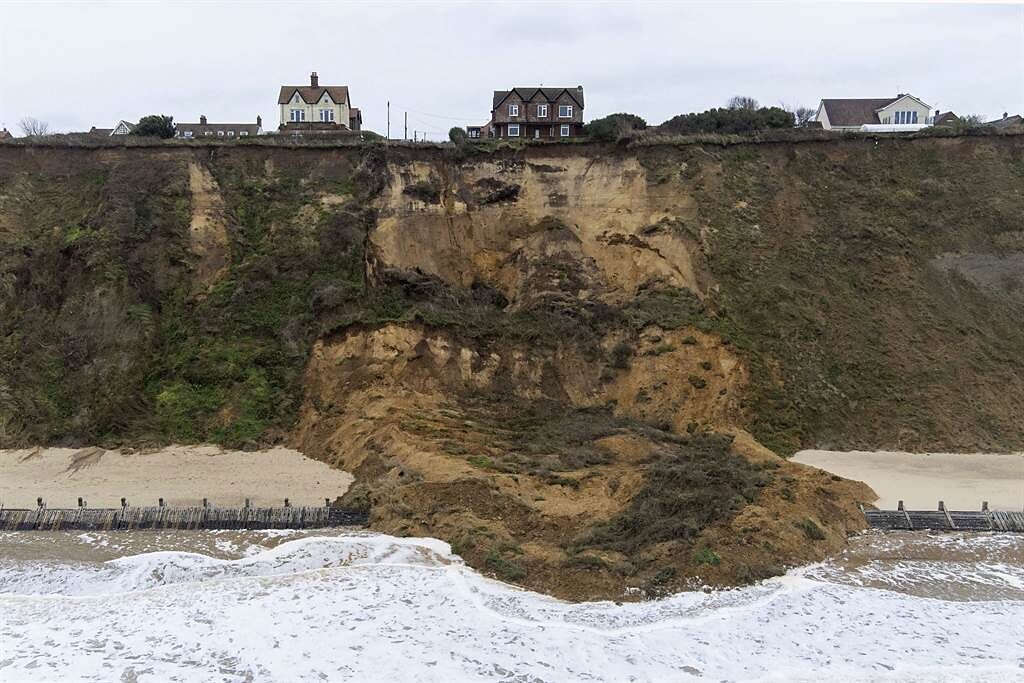 英國一處海濱區發生土石崩落意外，附近的住宅受到影響，住戶一覺醒來驚覺住在懸崖邊。(圖/美聯社)