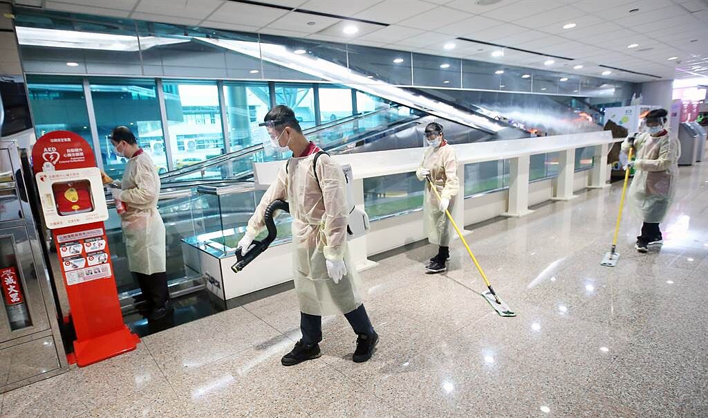 在桃機第二航廈入境大廳內，穿戴防護裝備的清潔人員正在消毒室內空間。（范揚光攝）