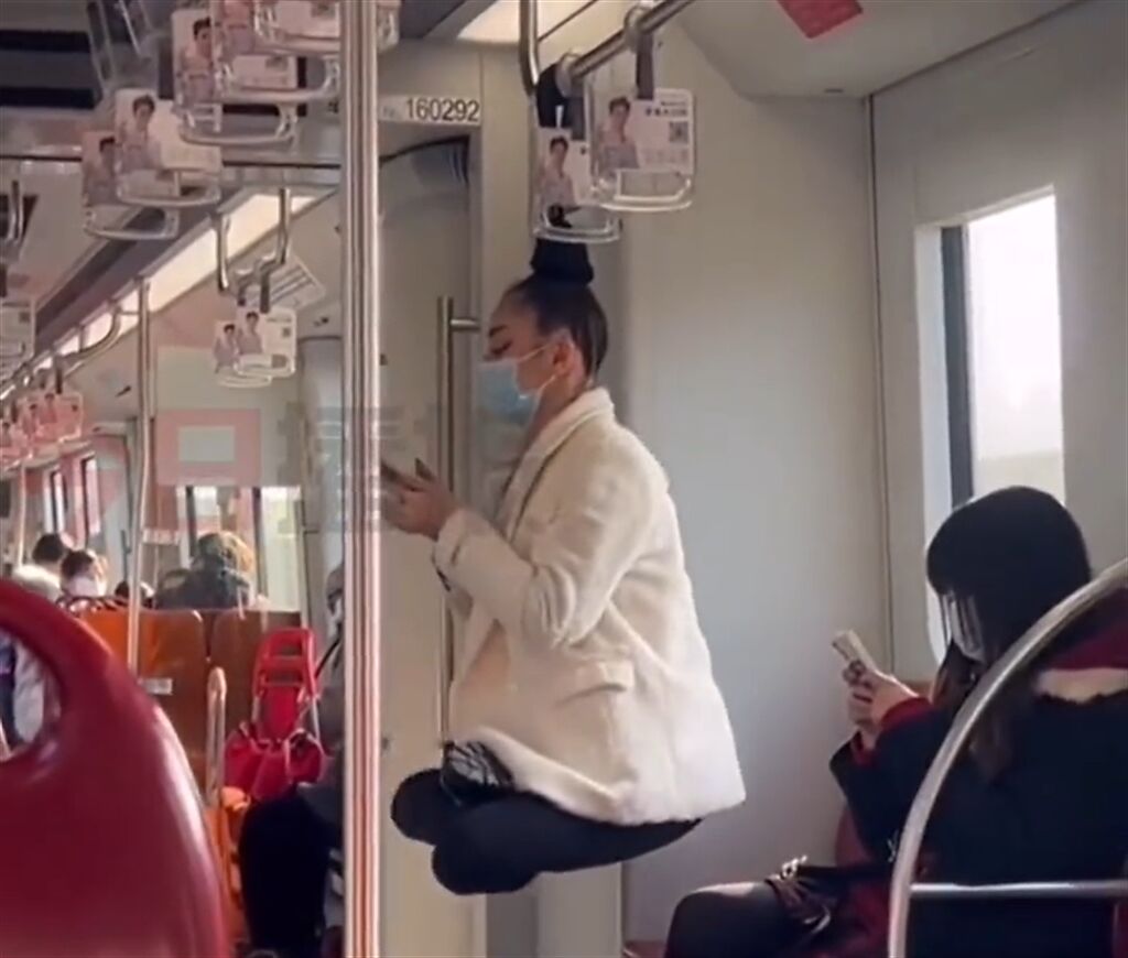 大陸上海地鐵出現「神燈女」凌空盤腿，竟將頭髮懸在把手盪鞦韆。(翻攝瀟湘晨報)