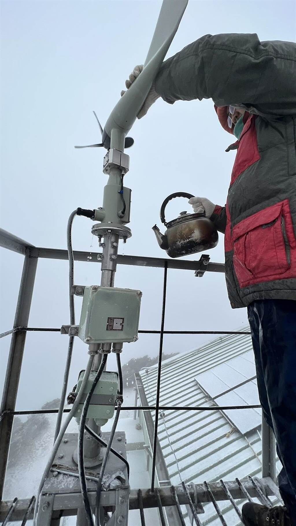 氣象站人員用熱水澆灌風向風速儀，讓儀器運作恢復正常。（玉山氣象站提供）