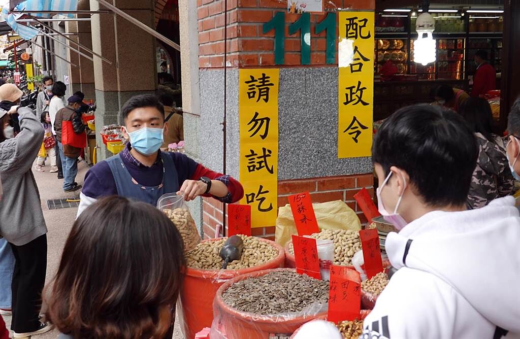 「台北市年貨大街」迪化街29日湧現搶辦年貨的人潮，店家設置看板呼籲民眾配合政令不要試吃。（姚志平攝）