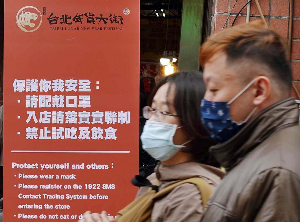  「台北市年貨大街」迪化街29日湧現搶辦年貨的人潮，入口處設置看板呼籲民眾配戴口罩，入店落實實聯制，並禁止試吃及飲食。（姚志平攝）