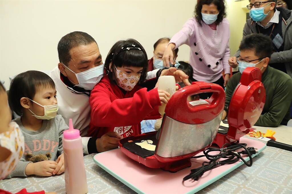 新北市長侯友宜和類家庭照顧的孩子蕾蕾，一起製作小魚兒雞蛋糕。（新北市新聞局提供）