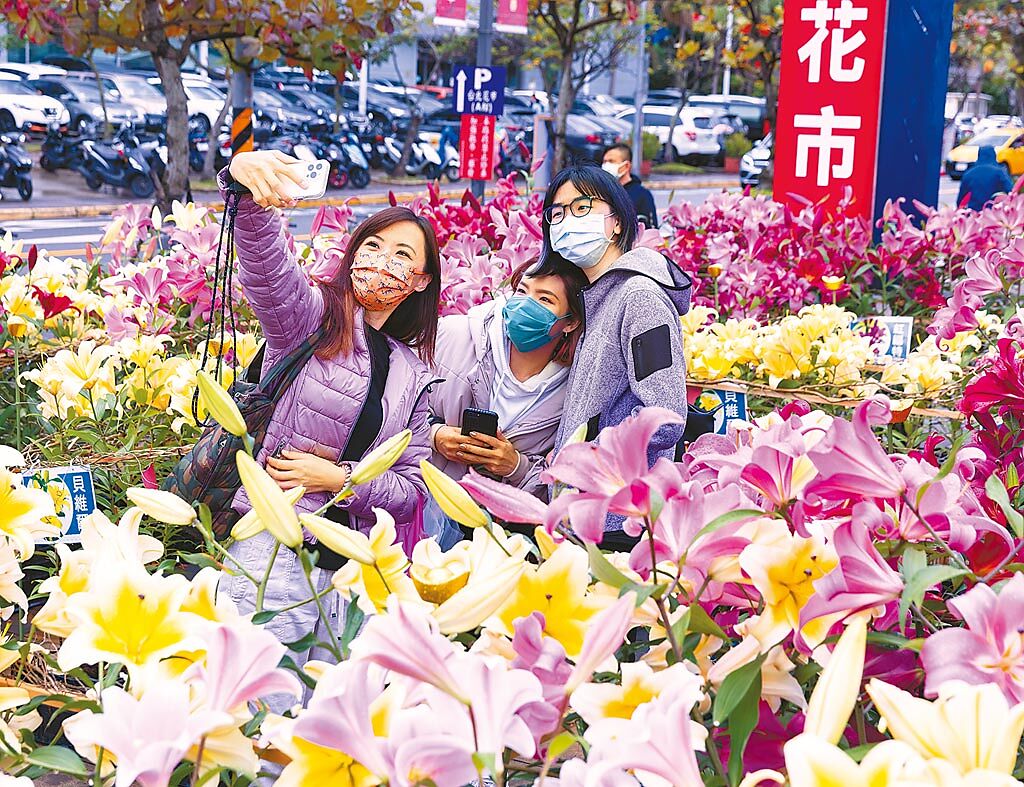 虎年年貨大採買，台北花市攤商擺出精美的新年飾品、花卉喜氣洋洋，民眾開心和鮮花自拍。（羅永銘攝）