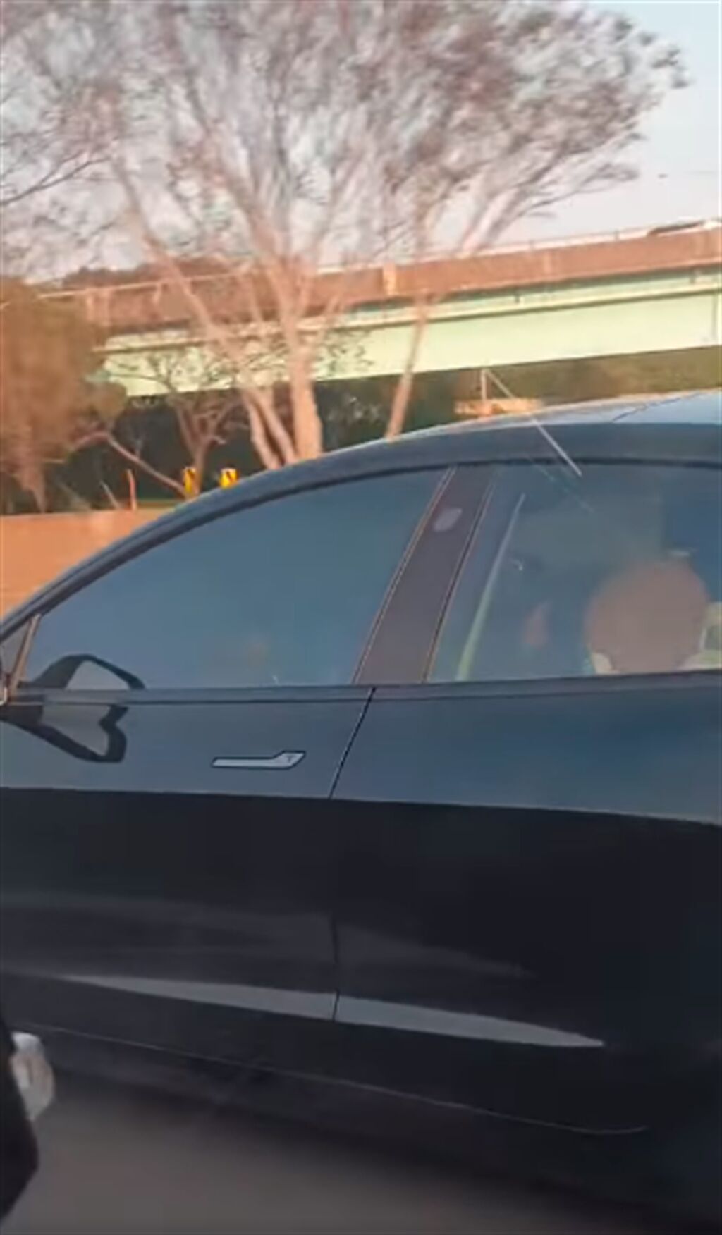 1名特斯拉駕駛疑似仗著有自動駕駛輔助系統，竟當在國道上「睡到歪頭」，遭其他車輛的乘客目擊後嚇壞拍下影片。（翻攝自臉書「爆廢公社」）