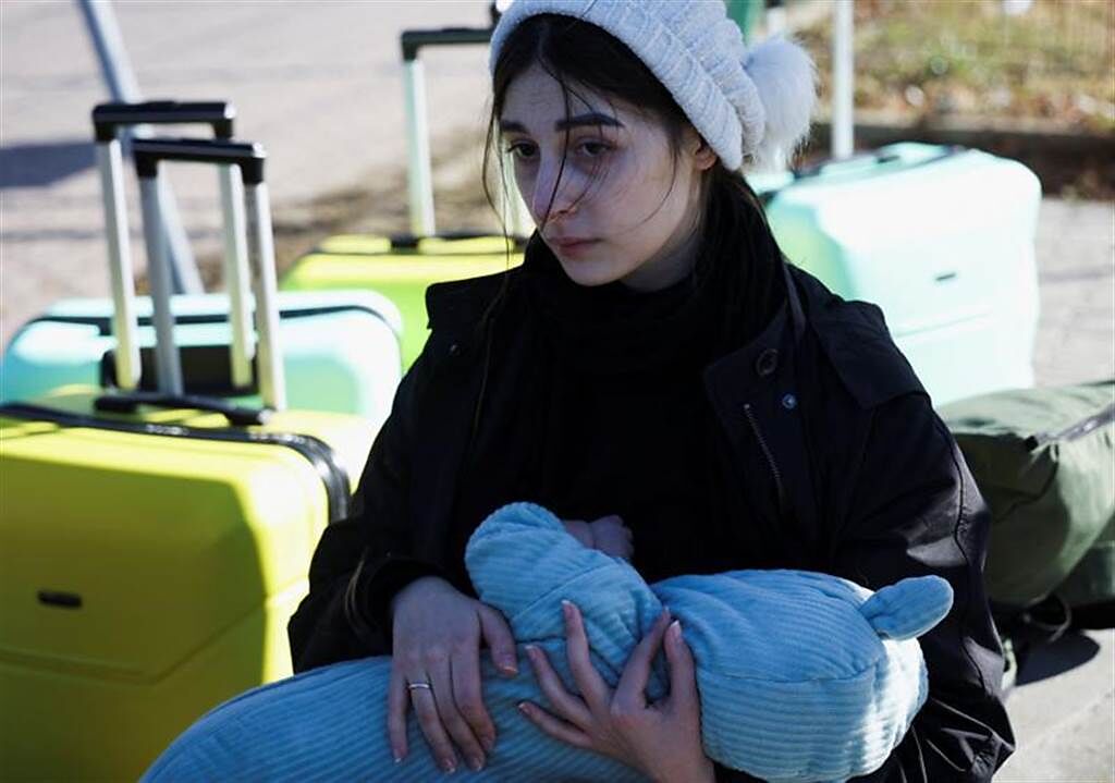 俄羅斯總統普丁於2月24日授權在烏克蘭東部進行軍事行動後，一名婦女坐在波蘭和烏克蘭之間的邊境口岸，抱著她的孩子。(圖/路透社)