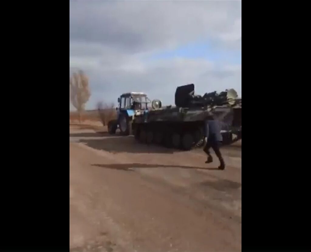 一輛俄羅斯裝甲車疑似遭烏克蘭拖拉機拖走，影片曝光引起廣大關注，在網路上被瘋傳，PTT網友直呼，像極了台灣常見的一幕。(圖截自推特/Johnny Mercer)
