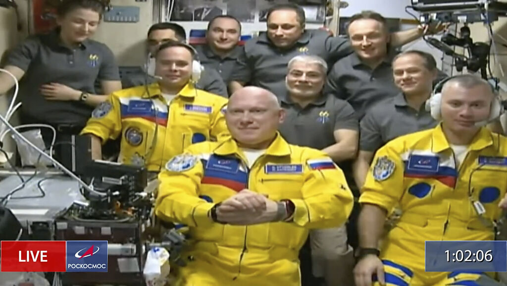 俄羅斯航太(Roscosmos)回傳的畫面截圖，三名太空人穿著黃藍配色飛行服。(圖/美聯社)  