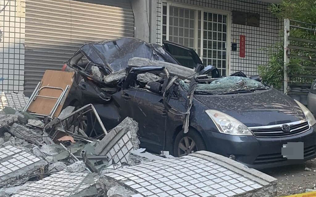 照片中1輛轎車停在1樓自家鐵門前慘遭樓上的大塊磁磚砸中，車頂當場被砸凹、破了大洞，整台車幾乎變成另類「敞篷車」。（警方提供）