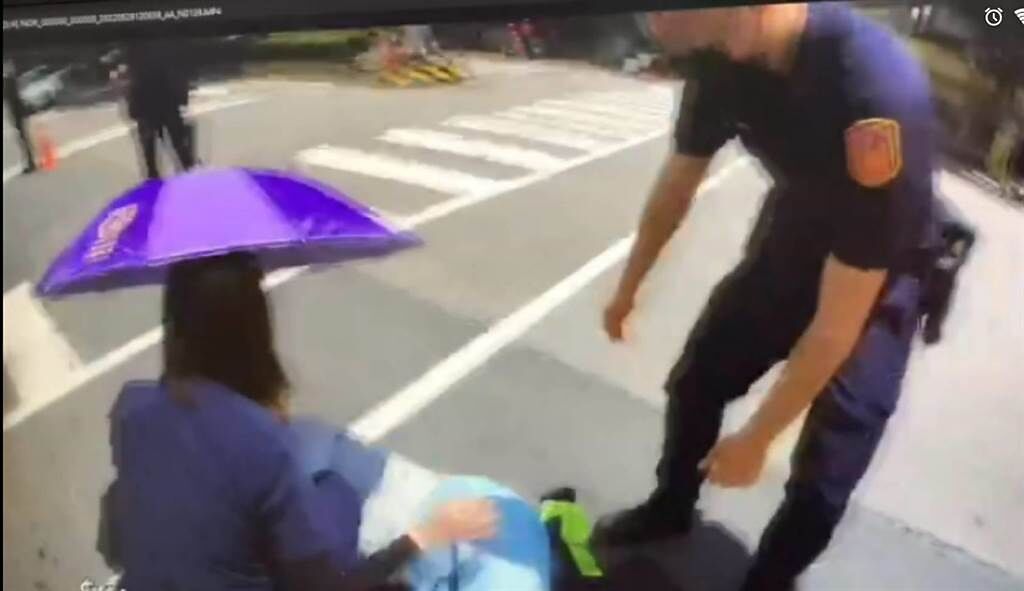 女警楊享蒴拿雨傘替傷者遮陽，並用雨衣墊在柏油路面上保護傷者。(翻攝照片／林郁平台北傳真）