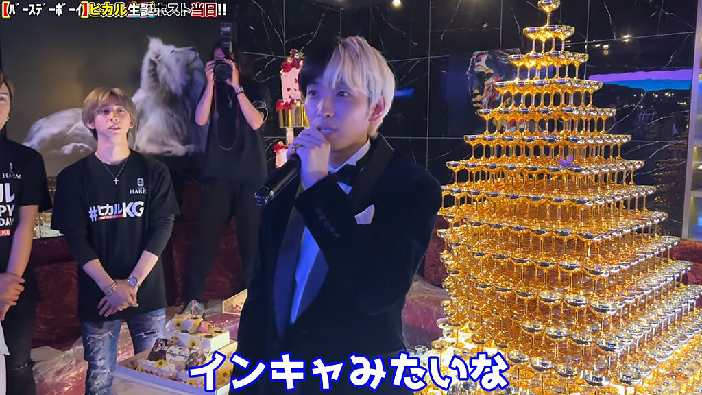 Hikaru身後堆疊豪華香檳塔，可見粉絲們相當捧場他的場子。(圖/Hikaru Youtube)