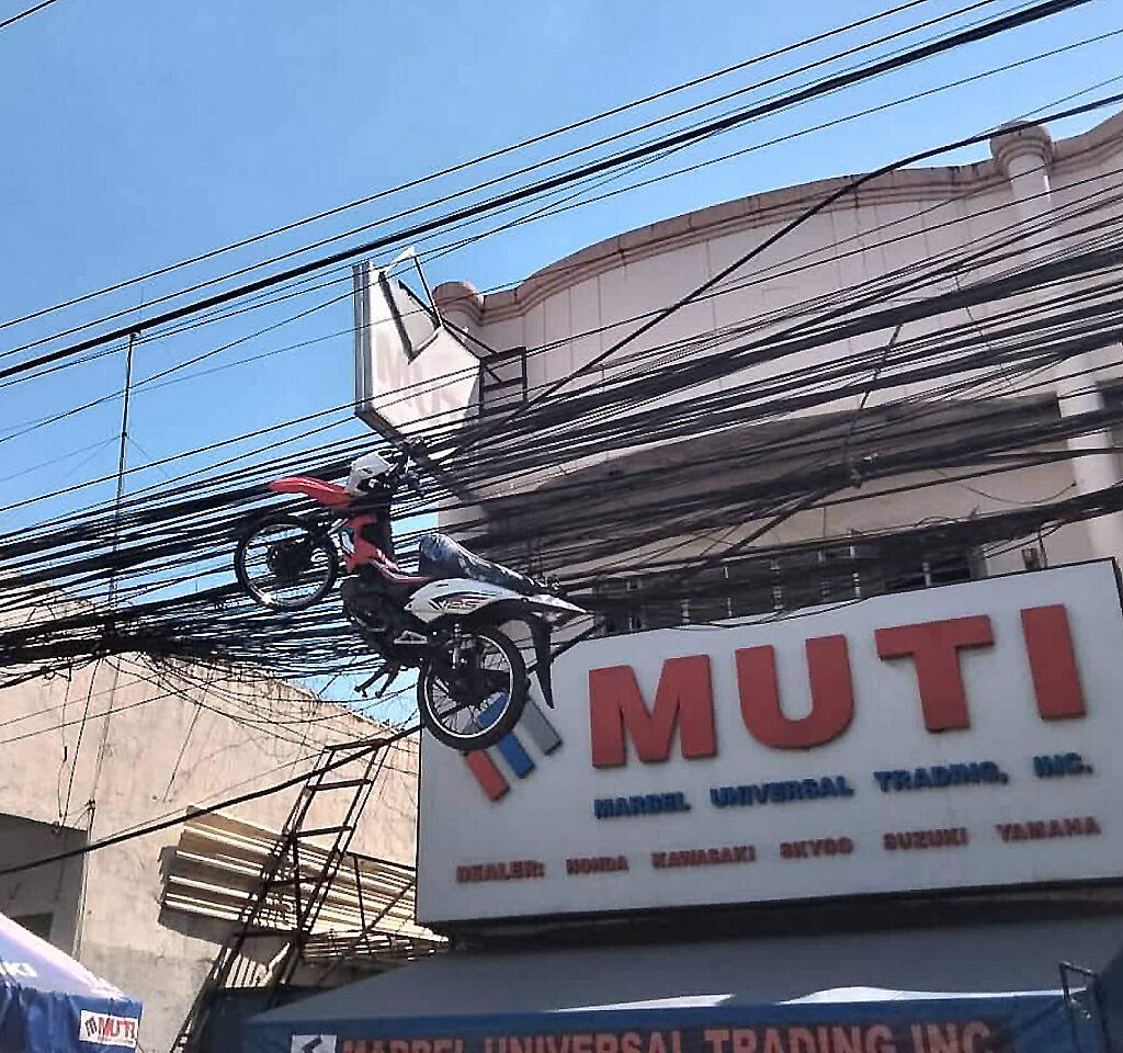 菲律賓一輛電動機車被電纜纏住，直接懸掛在半空中。（圖／翻攝自臉書）