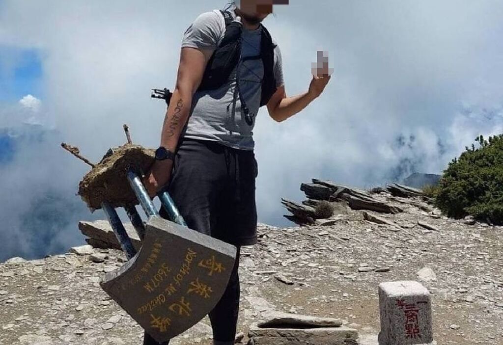 男子登上奇萊北峰，竟然拆下標誌拍照留念，遭網友罵翻「會不會太離譜」。（翻攝自記者爆料網）